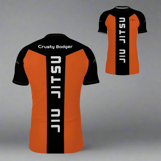 Orange and black jiu jitsu rash guard with 'Crusty Badger' and 'Jiu Jitsu' branding on a white background.