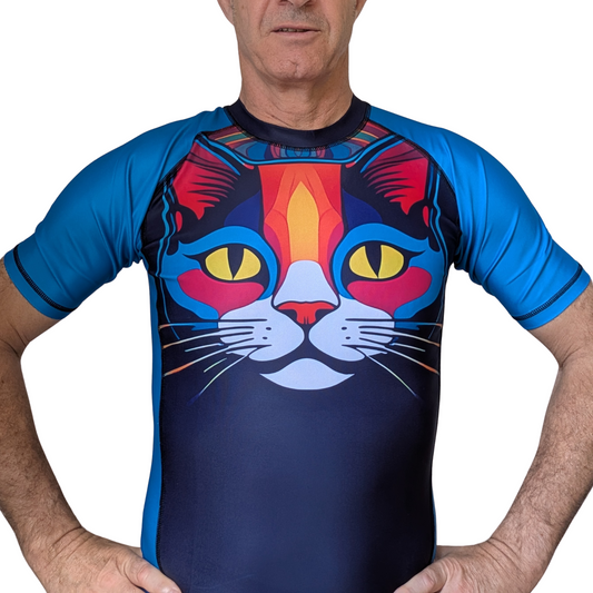 Person wearing a colorful cat-themed  BJJ rash guard  with blue sleeves on a white background