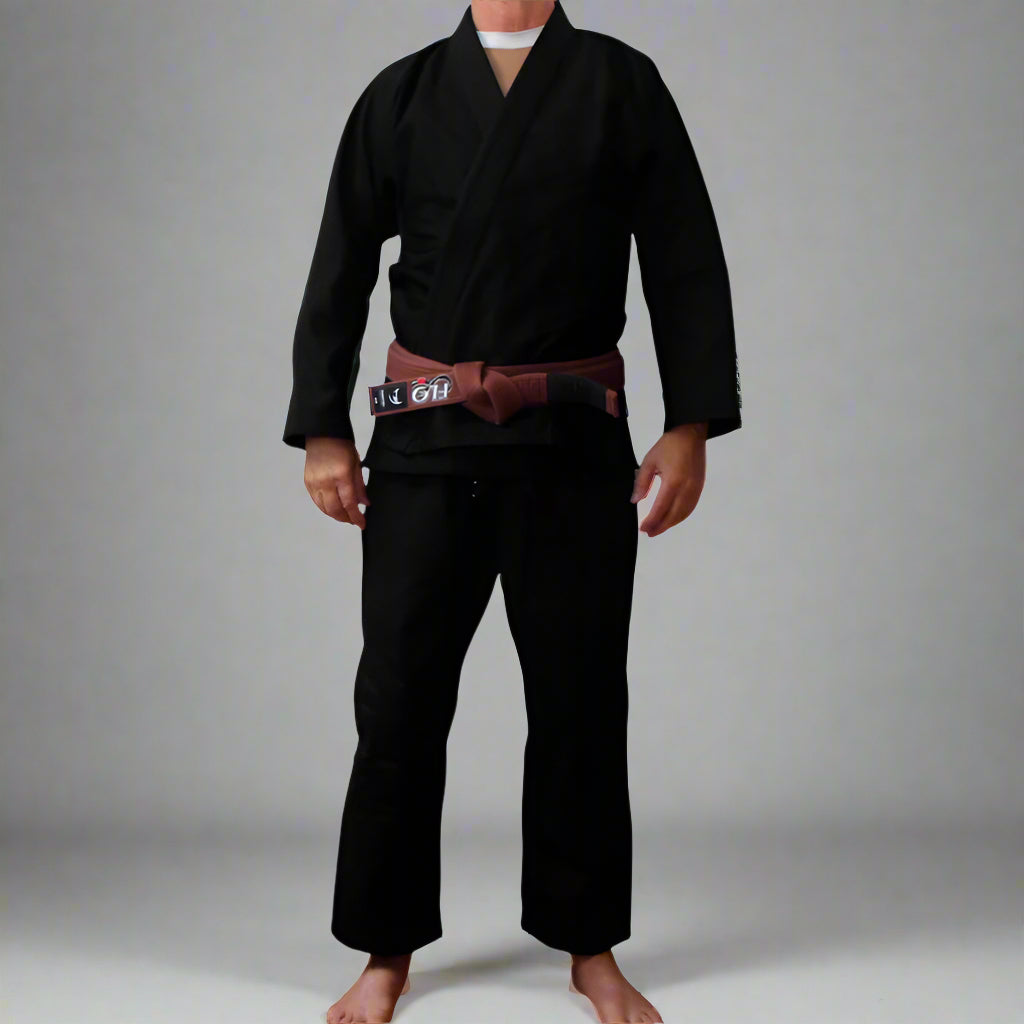 Person wearing a black BJJ gi with a brown belt on a white background