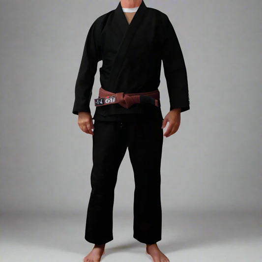 Person wearing a black BJJ gi with a brown belt on a white background
