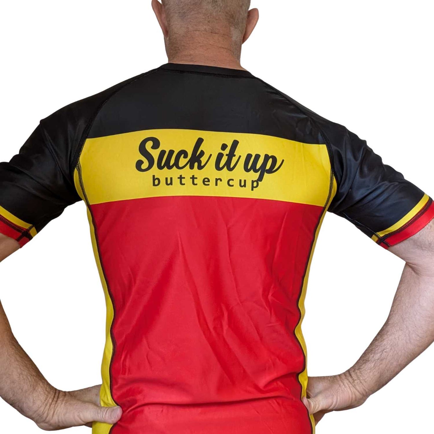 Person wearing a red, yellow, and black BJJ rash guard with text on the back.
