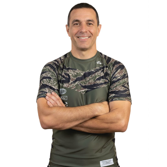 Man wearing a green camouflage BJJ rash guard with a white background